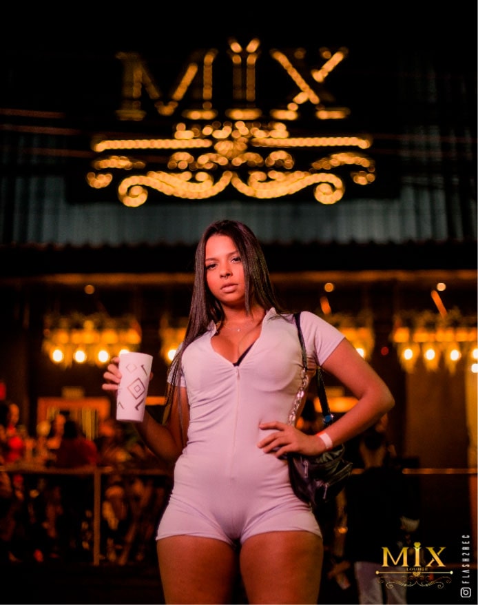 Garota com copo na mão em frente ao Mix Lounge